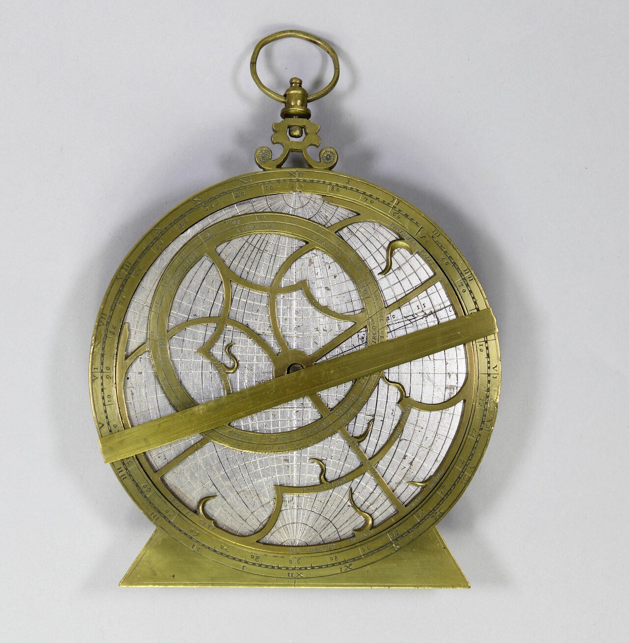 An engraved brass astrolabe on a pale surface